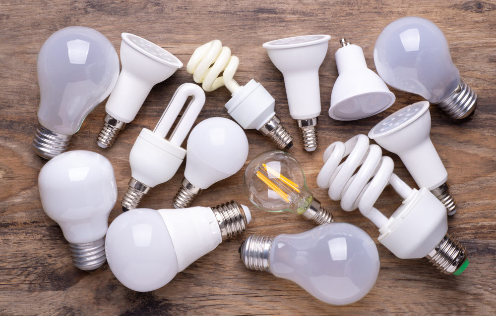 Assorted energy-efficient light bulbs including LEDs and CFLs on a wooden surface.