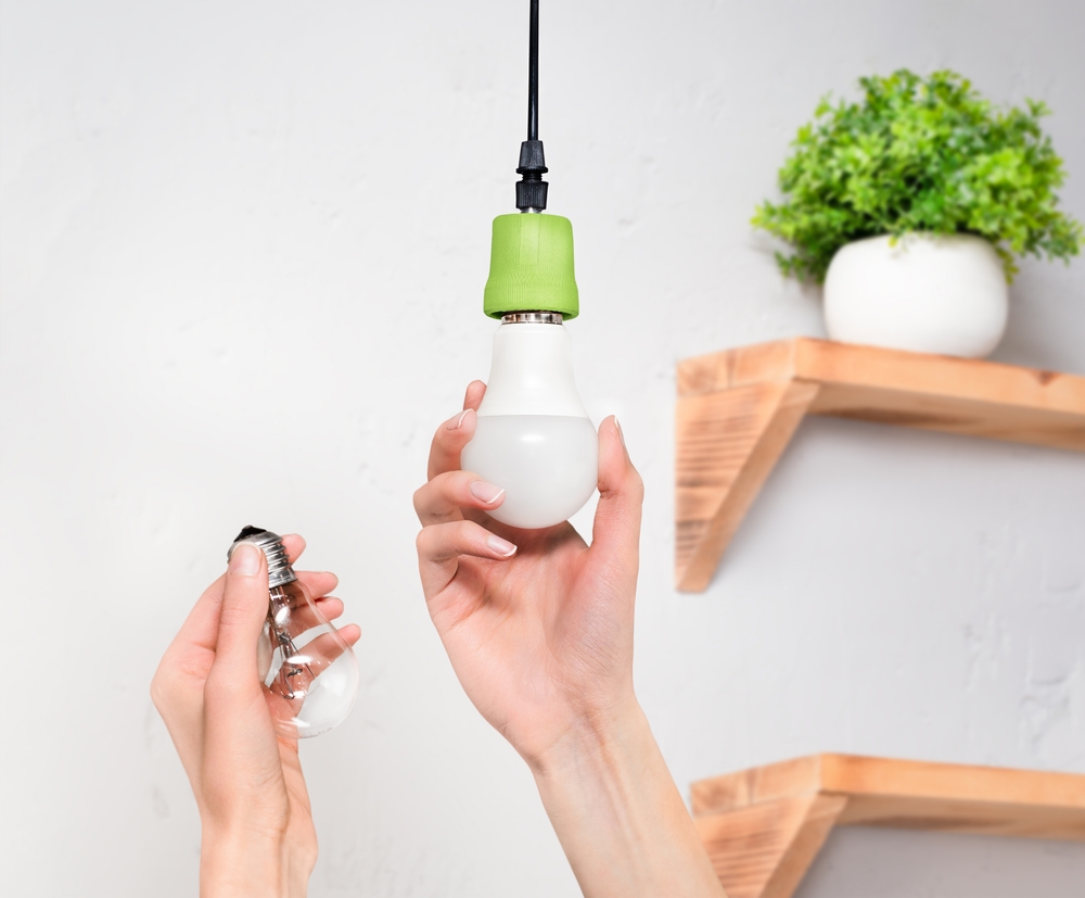 Hand replacing incandescent bulb with energy-efficient LED bulb 