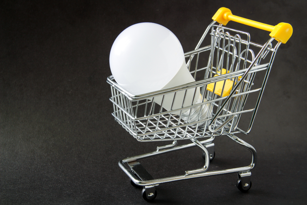 LED bulb in a miniature shopping cart symbolizing the purchase of energy-efficient lighting.